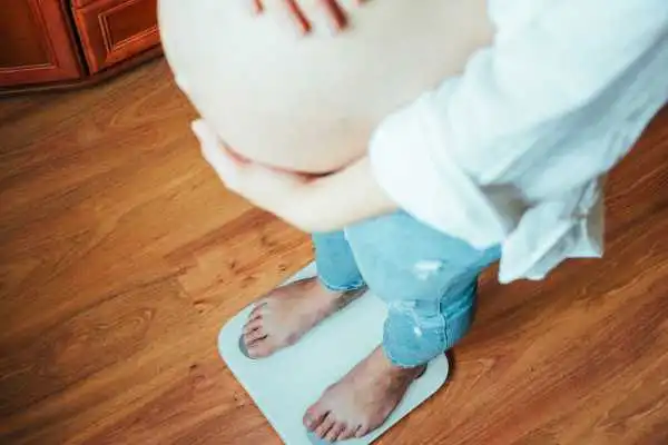 Image of woman weighing herself and experiencing weight gain through pregnancy Stourbridge